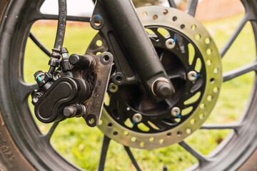 Black motorcycle front disc brakes damaged wheel on a sunny day with cloudy sky