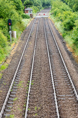 Obraz premium High level vertical view of train tracks diappearing around bend in distance and fence over tracks just outside station of Llanfairpwllgwyngyll, UK