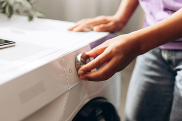 Housewife using washing machine at home, setting washing cycle