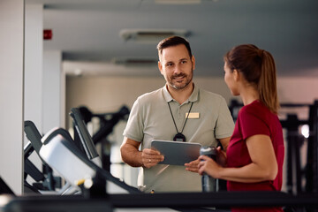Fitness instructor talking to sportswoman during exercise class at health club.