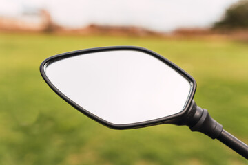 Black motorcycle rearview mirror and motorcycle handlebar on a sunny day of travel