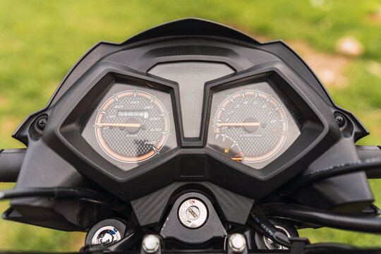 Black motorcycle dashboard on a sunny day with a cloudy sky