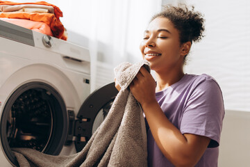Housewife smelling fresh towel after laundry in washing machine