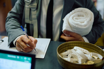 Close up of businessman signing in at gym's reception desk.