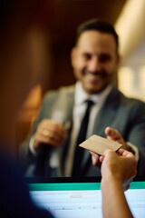 Close up of receptionist giving membership card to businessman at gym.