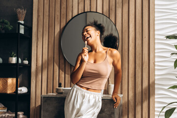 Young woman brushing teeth with sustainable wooden toothbrush in modern bathroom