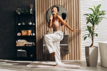 Young woman dancing and brushing teeth in modern bathroom