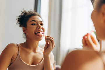 Young woman cleaning her tongue in front of mirror