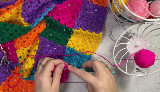 Crocheting granny square blanket plaid process and woman's hands hobby handmade handiwork clews and hook cozy winter autumn fall video	
