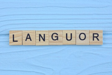 word languor made from wooden gray letters lies on a blue background