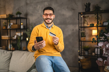 adult young man buy online on cellphone with credit card at home