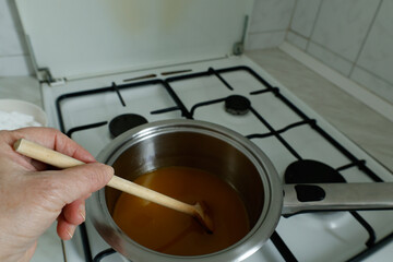 A block of butter melting in a stainless steel saucepan on a gas stove. 