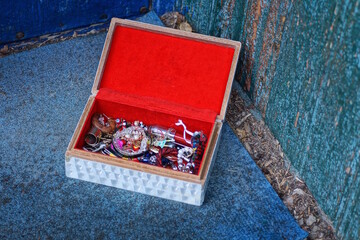 colorful jewelry and costume jewelry lie in a red white open box stands on a blue table near a...