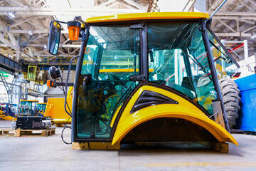 New tractor cabin or combine harvester on the assembly line of a tractor factory. Manufacturing of...