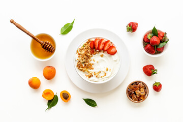 Bowl with yogurt and oatmeal served with honey and strawberry, top view