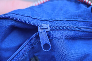 one open small metal plastic zip on blue fabric clothes pants