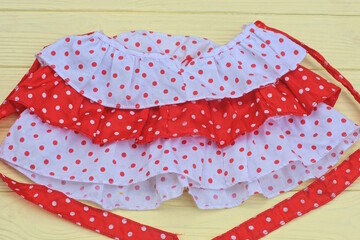 one small women's skirt made of striped fabric with frill and white red polka dots lies on a yellow...