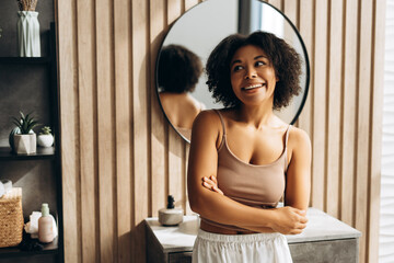 Smiling woman crossing arms in modern bathroom