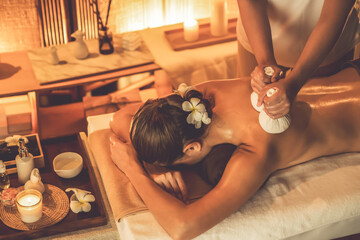 Hot herbal ball spa massage body treatment, masseur gently compresses herb bag on woman body....