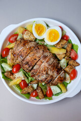 Healthy organic chicken salad with roasted sesame dressing. Grilled chicken breasts and fresh vegetables in a plate.