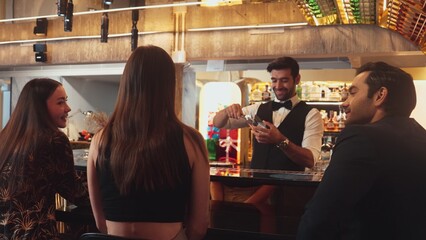 Smart bartender with VIP customer at luxurious bar greeting new beautiful guest at counter in engaging lively conversation at back view in lighting atmosphere at lighting warm nightclub. Vinosity.