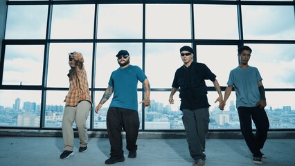 Group of multicultural dancer dancing together with skyscraper. Portrait of multicultural hipster team moving foot step with confident near window with urban city view. Outdoor sport 2024. Hiphop.