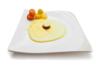 Condensed milk and custard desert looks like a fired egg and colorful jelly sweets in sugar on a white fancy square plate and light background. Creative food ideas. Light and airy look