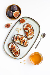 Figs and cheese toasts on the plate with jar of honey, top view