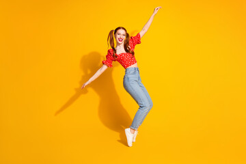 Photo portrait of young red hair funky positive girl wearing blouse and jeans dancing standing tiptoes isolated on yellow color background