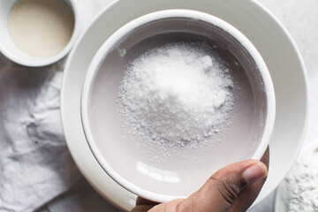 Overhead view of white sugar in a grey plate, top view of granulated sugar in a plate