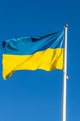 The Ukrainian flag flutters in the wind against the background of the blue sky