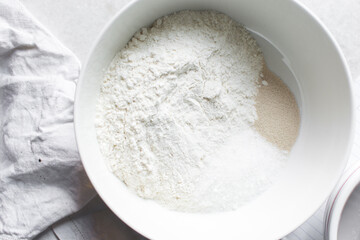 Mise en place of ingredients for making bread, All purpose flour salt and yeast in a white bowl, process of making bread