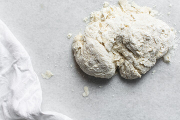 Overhead view of challah dough being kneaded on a white countertop, top view of homemade challah dough being mixed on white granite countertop, process of making challah