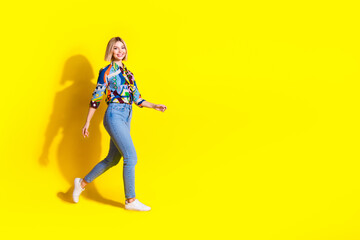 Full body photo of attractive young woman walking black friday dressed stylish colorful clothes isolated on yellow color background