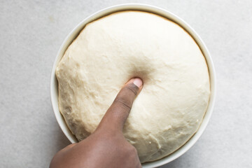 Overhead view of proofed bread dough, Checking if dough is proofed using a finger poke test, process of making bread