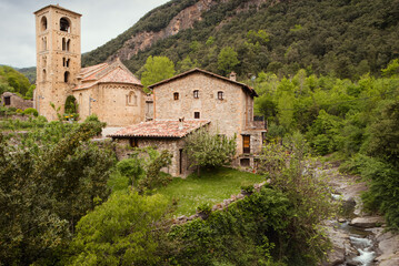 Scenic View of Medieval Stone Buildings and Church in Beget, Girona Surrounded by Lush Greenery and Mountains