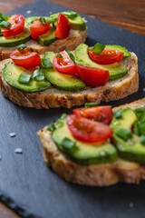 Avocado toast topped with tomato and green onion on a slice of carrot bread