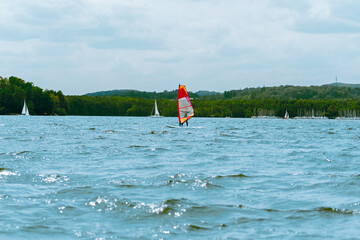 Windsurfer on Scenic Lake with Other Sailboats in a Natural Landscape