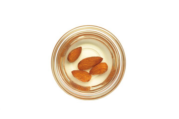 Fresh almond oil with almond nuts in glass bowl isolated on white background.