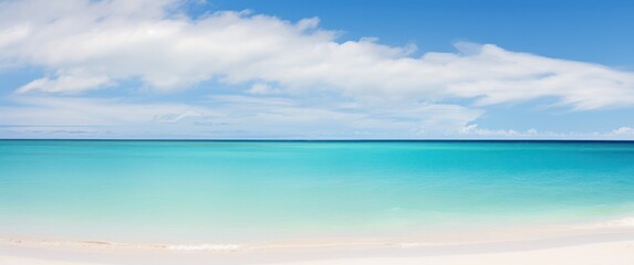 Fototapeta premium A serene beach scene featuring a clear turquoise ocean under a bright blue sky with fluffy white clouds inviting tranquility and relaxation.