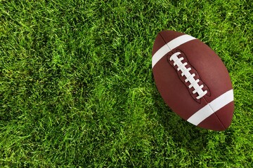 Obraz premium A brown leather ball American football on green field