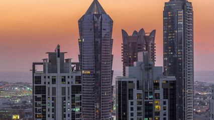 Fototapeta premium View of illuminated skyscrapers with lights from windows in Dubai at sunset aerial timelapse