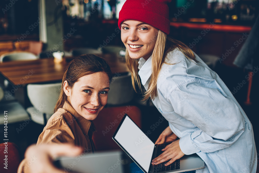 Poster half length portrait of happy hipster girls dressed in casual outfit smiling at camera while updatin