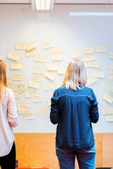 Collaborative Team Brainstorming in Front of Idea Board Covered in Sticky Notes
