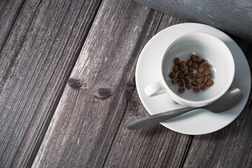 Isolated cup and saucer filled with coffee beans and spoon