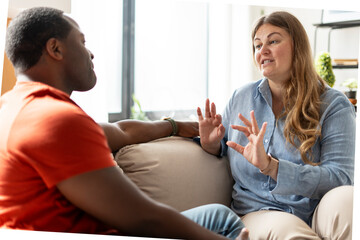 Plus size woman explaining for man, gesturing with hands at home