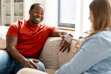 Obraz premium Happy middle aged African American guy looking at woman talking in room at home