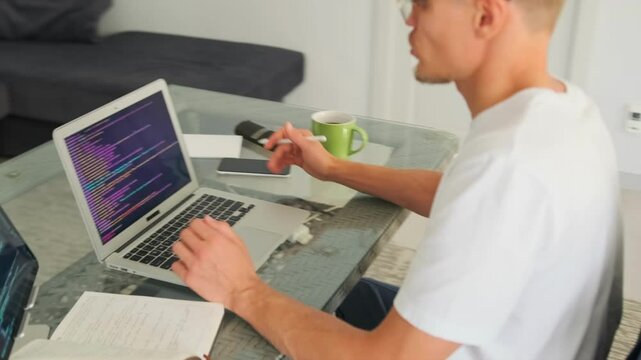 Senior programmer focuses on debugging during video call in modern room.