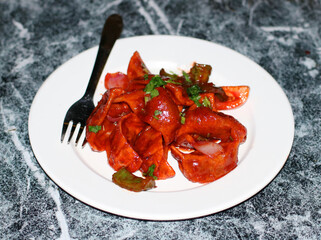 Chilly momo served on a white plate, garnished with fresh herbs and vegetables, showcasing a vibrant and spicy dish.