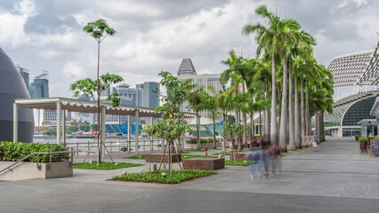 Walk way with palms beside at parks and outdoor of marina bay with Singapore skyscrapers skyline timelapse hyperlapse
